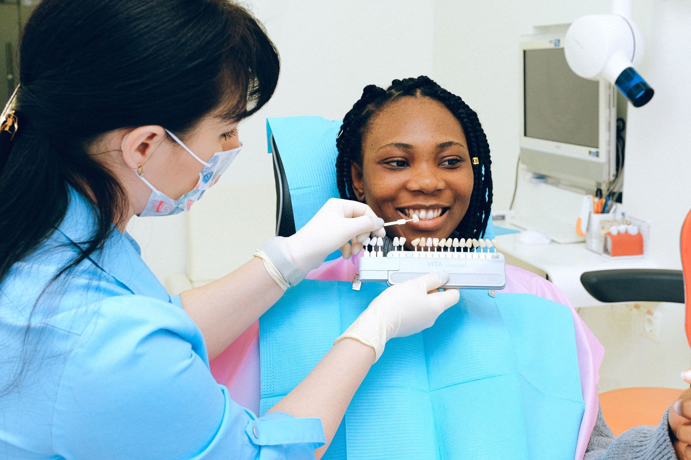 Smiling patient matching tooth shades with a whitening shade guide